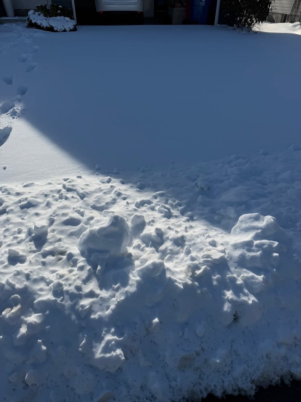 A driveway buried under fresh snow before Precision Outdoor Solutions cleared it
